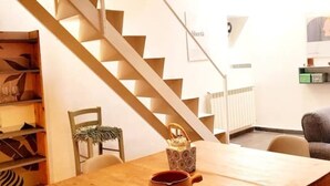 A staircase with a modern design, a dining table with chairs, and a small table with a decorative item.