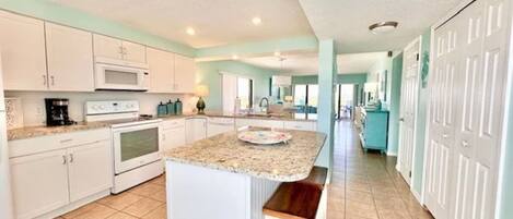 A spacious kitchen with white cabinets, a granite countertop, and a central island with a bench.