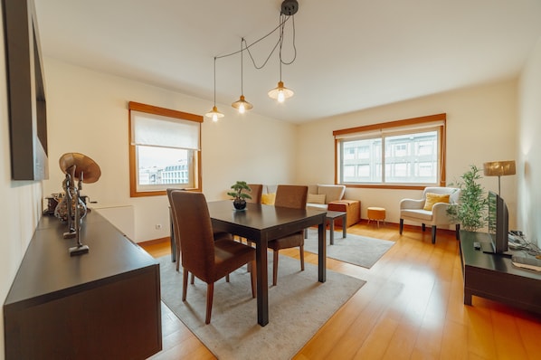 Una sala moderna con una mesa de comedor, sillas, un sofá y un mueble para televisión.