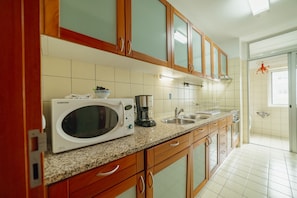 A kitchen with wooden cabinets, a microwave, a coffee maker, and a sink. - Downtown Deluxe 6 by Vacationy (Porto)