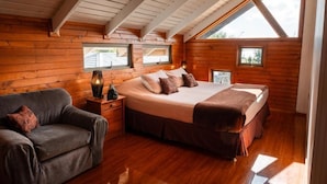 Une chambre confortable avec un grand lit, un plafond en bois et deux fenêtres.