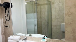 Une salle de bain avec un lavabo, un miroir et un sèche-cheveux fixés au mur.