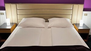 Un lit avec une tête de lit, deux tables de chevet et un mur violet.