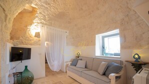 Habitació acollidora amb sostre de pedra, un sofà, una televisió i un gran vas.