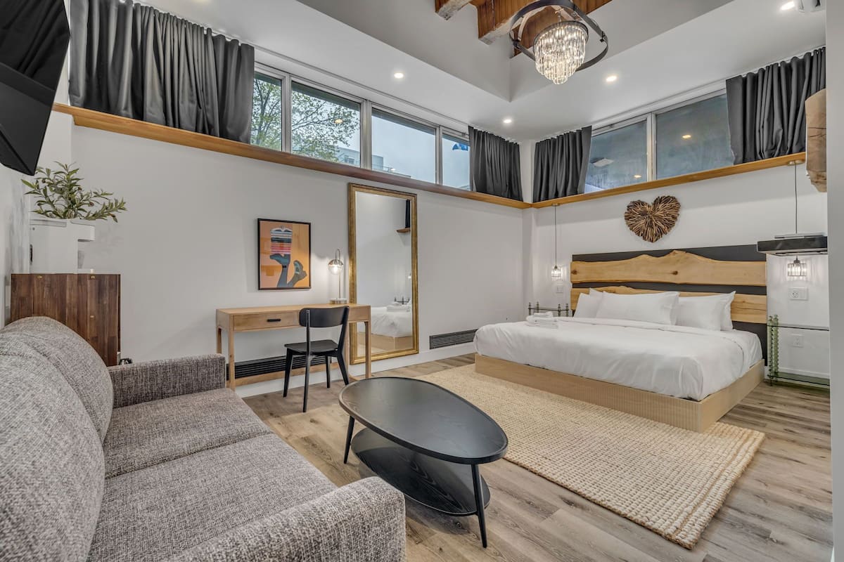 A modern bedroom with a bed, desk, and seating area.