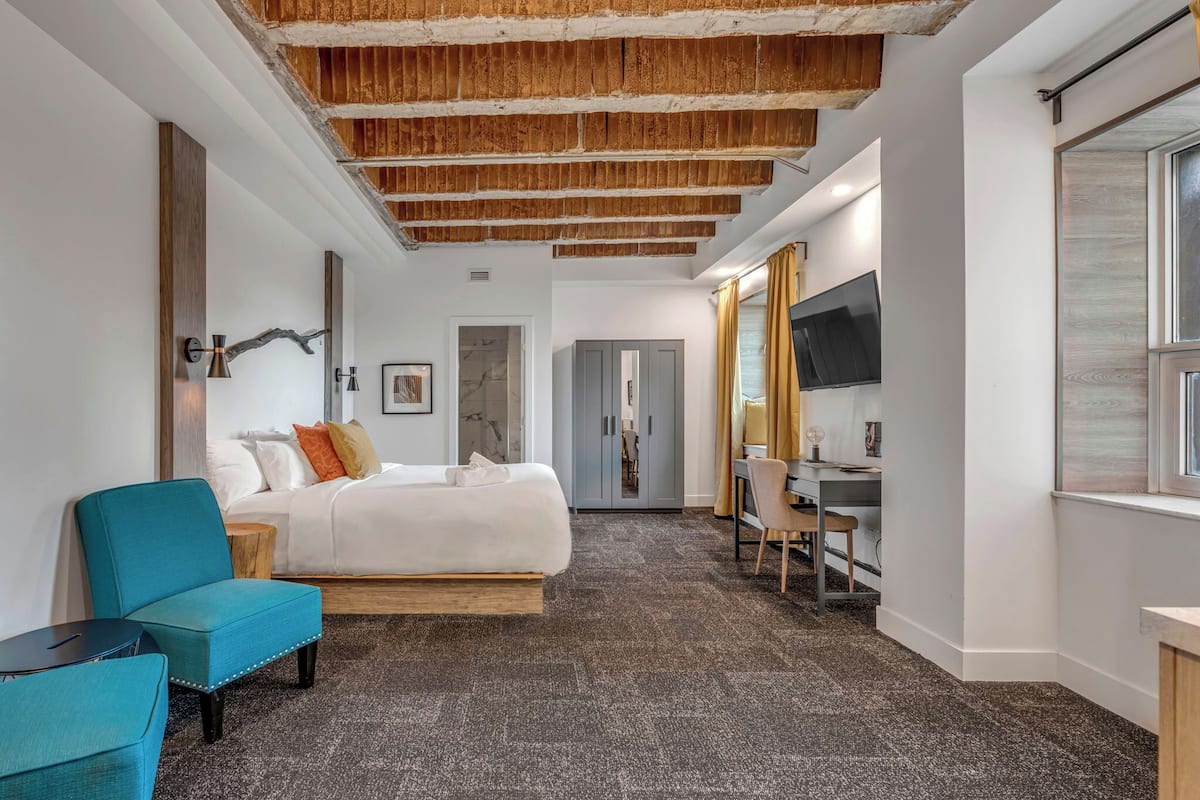 A modern hotel room with a bed, a desk, and a chair.
