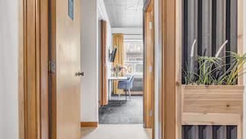 A hallway with wooden doors, a small table with chairs, and a potted plant.