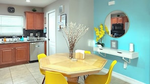 A kitchen with wooden cabinets, a dining table with yellow chairs, and a vase with flowers.