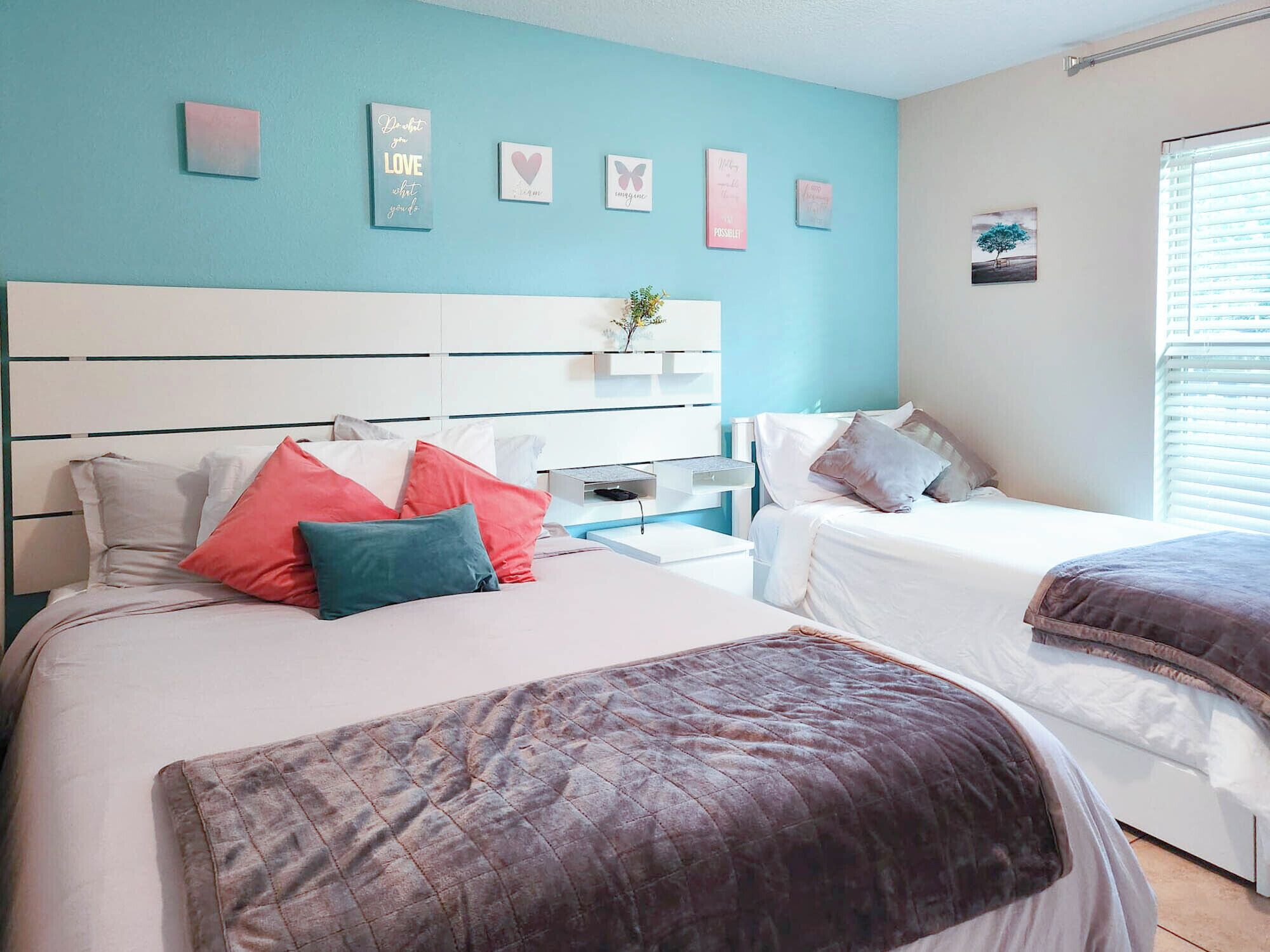 Une chambre avec deux lits, une tête de lit blanche et un mur d’accent bleu.