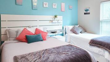 Une chambre avec deux lits, une tête de lit blanche et un mur d’accent bleu.