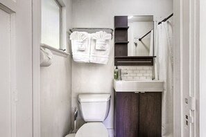 A bathroom with a toilet, a sink, a mirror, and a shower curtain. - Timeless Charm, Modern Comfort close to everything (Sonoma)