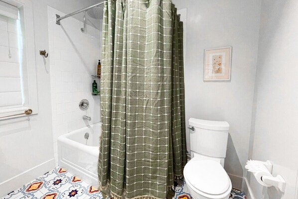 Une salle de bain avec une baignoire, des toilettes et un rideau de douche.