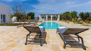 Ein Poolbereich mit Liegestühlen und einer Pergola.
