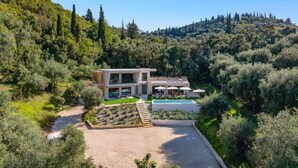 A modern two-story house with a swimming pool, surrounded by lush greenery and hills. - Villa Optima by Villa Plus (Ionian Islands)