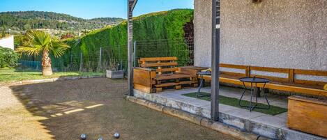 A rustic outdoor seating area with a pergola, wooden benches, and a table.