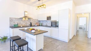 A modern kitchen with white cabinets, a central island, and a built-in oven.