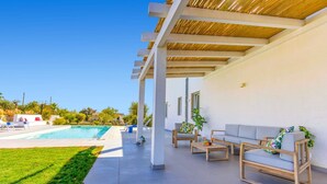 A covered outdoor area with a pool, seating, and a pergola.
