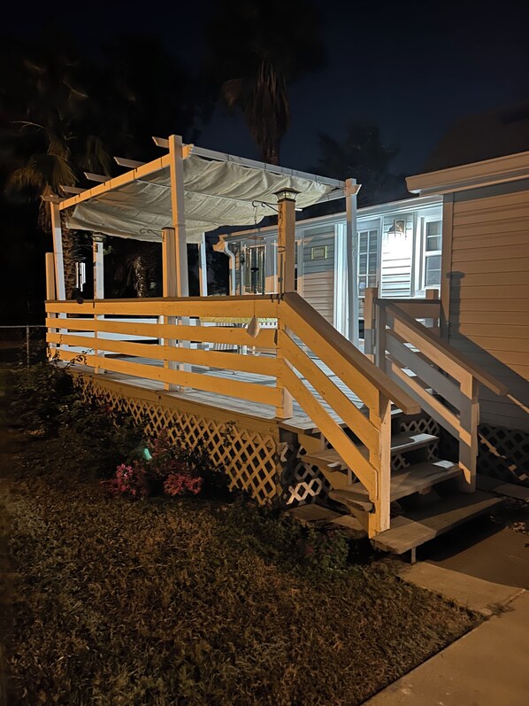 Une petite maison de plain-pied avec une terrasse en bois et un porche couvert.