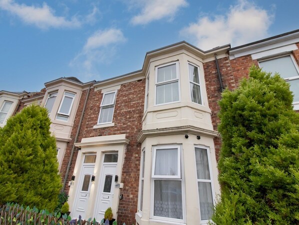 A row of terraced houses with bay windows and white doors.