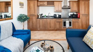 A compact living space with a kitchenette, two sofas, a coffee table, and a mirror.