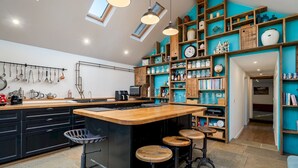 Cozinha moderna com ilha central, banquetas e diversos utensílios e eletrodomésticos.