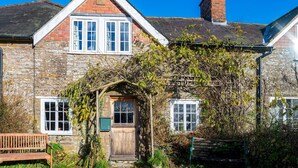 Une maison en pierre avec une porte en bois, un petit porche et un banc.