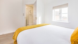 Quarto com cama, janela e área de chuveiro.