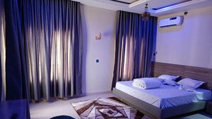 Un dormitorio moderno con cama, cortinas, alfombra y lámpara de techo.