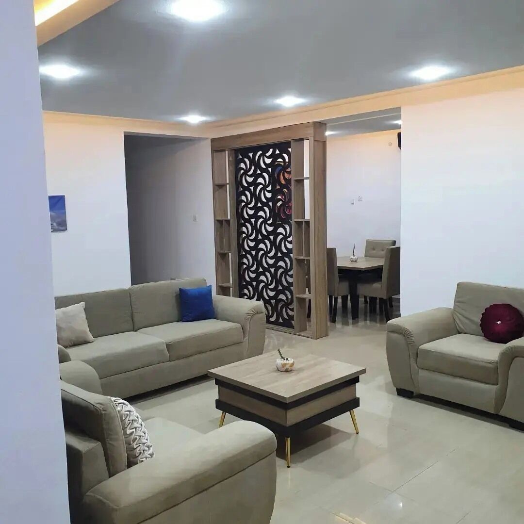 A modern living room with a sofa set, a coffee table, and a decorative partition.
