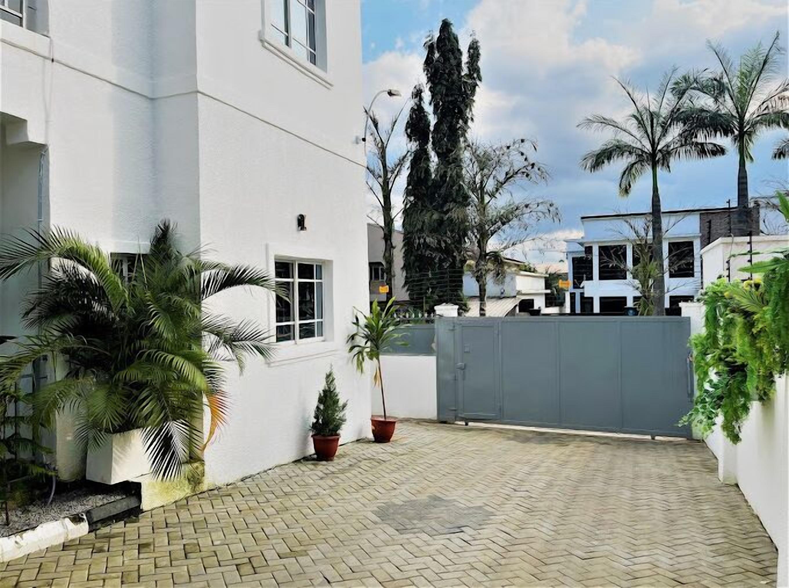 A courtyard with a paved floor, white walls, and potted plants.