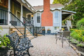 A brick house with a porch, outdoor seating, and a garden. - (D) Elora Lower Banks Suite (Elora)