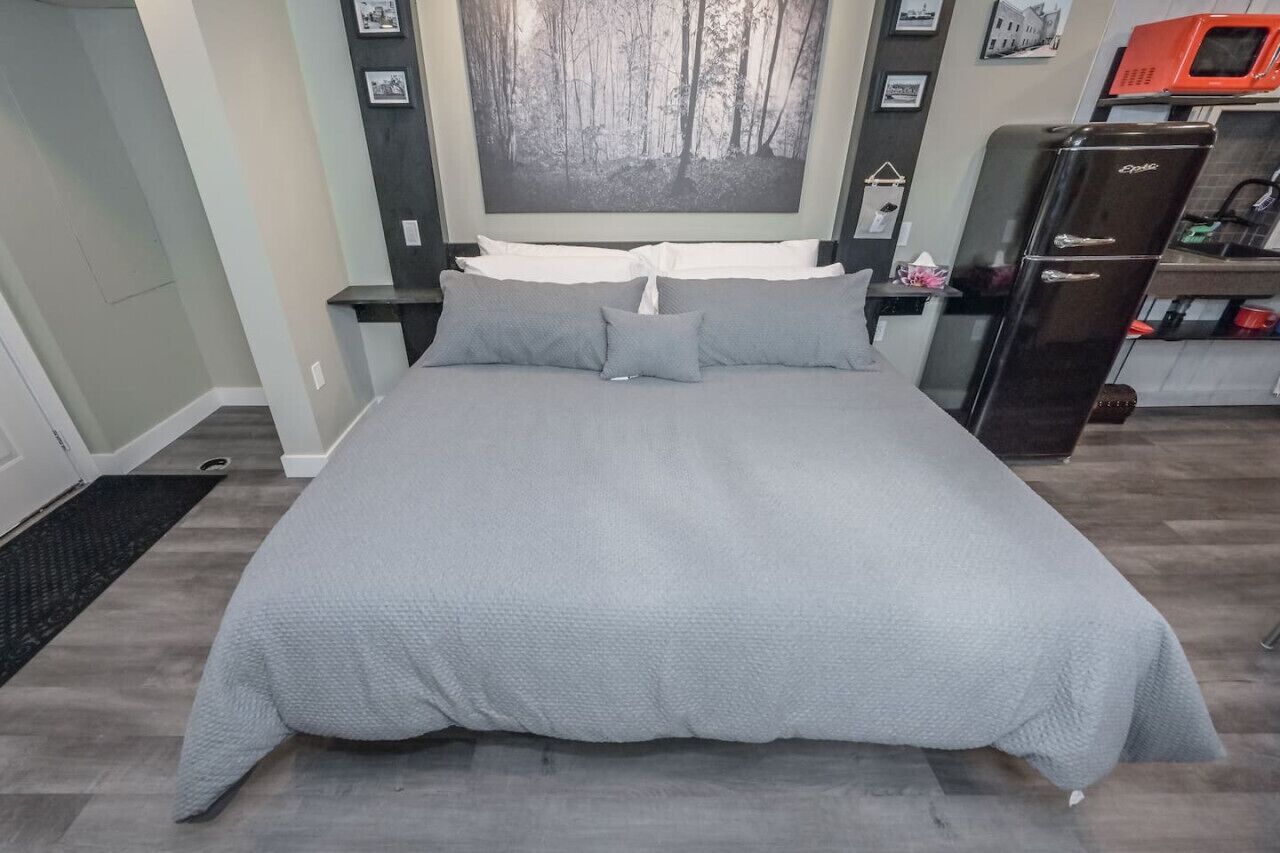 Une chambre avec un grand lit, une table de chevet, une commode, un four à micro-ondes et un réfrigérateur.