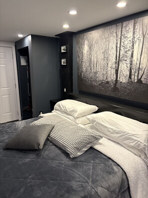 Ein Schlafzimmer mit einem Bett, einem großen Wandbild mit Waldmotiv und einem Einbauschrank.
