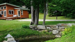 Un chalet rustique avec un mur en pierre et un petit ruisseau qui le borde.
