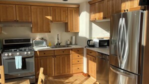 Une cuisine moderne avec des meubles en bois, des appareils électroménagers en acier inoxydable et une table à manger en bois.