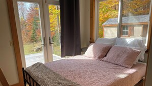 Une chambre à coucher avec un lit, une fenêtre et une vue sur les arbres.