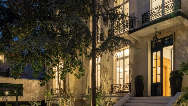 Un cortile con un divano, gradini che portano all'ingresso di un edificio e piante in vaso.