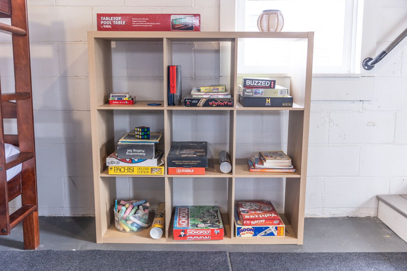 A wooden bookshelf with various board games and puzzles.