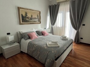 A bedroom with a bed, nightstand, and a painting on the wall. - ALGA Roma Apartment (Roma)