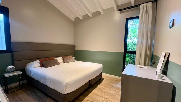 Un dormitorio con cama, mesita de noche y escritorio con silla.