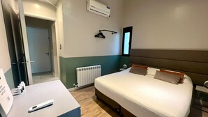 Una habitación de hotel con cama, mesita de noche y radiador.