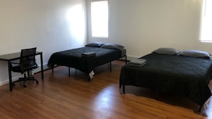 Una habitación con dos camas, un escritorio y una silla.