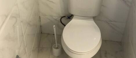 A toilet in a bathroom with marble walls and floor.