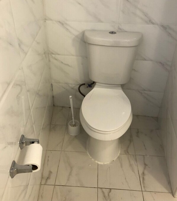 A toilet in a bathroom with marble walls and floor.