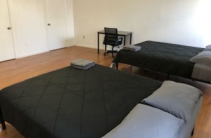 A room with two beds, a desk, and a chair.