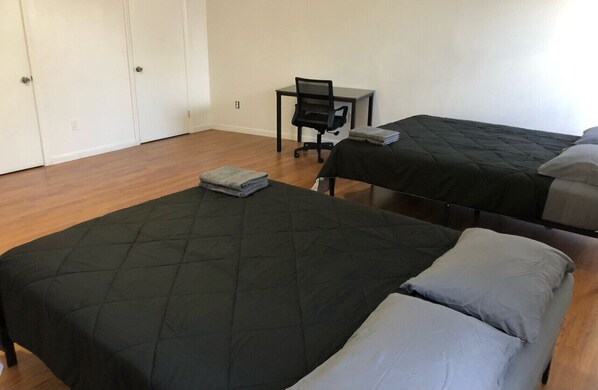 A room with two beds, a desk, and a chair.