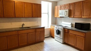 Una cocina con armarios de madera, una estufa blanca, un microondas y un fregadero.