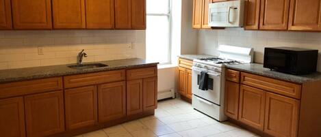 A kitchen with wooden cabinets, a white stove, a microwave, and a sink.