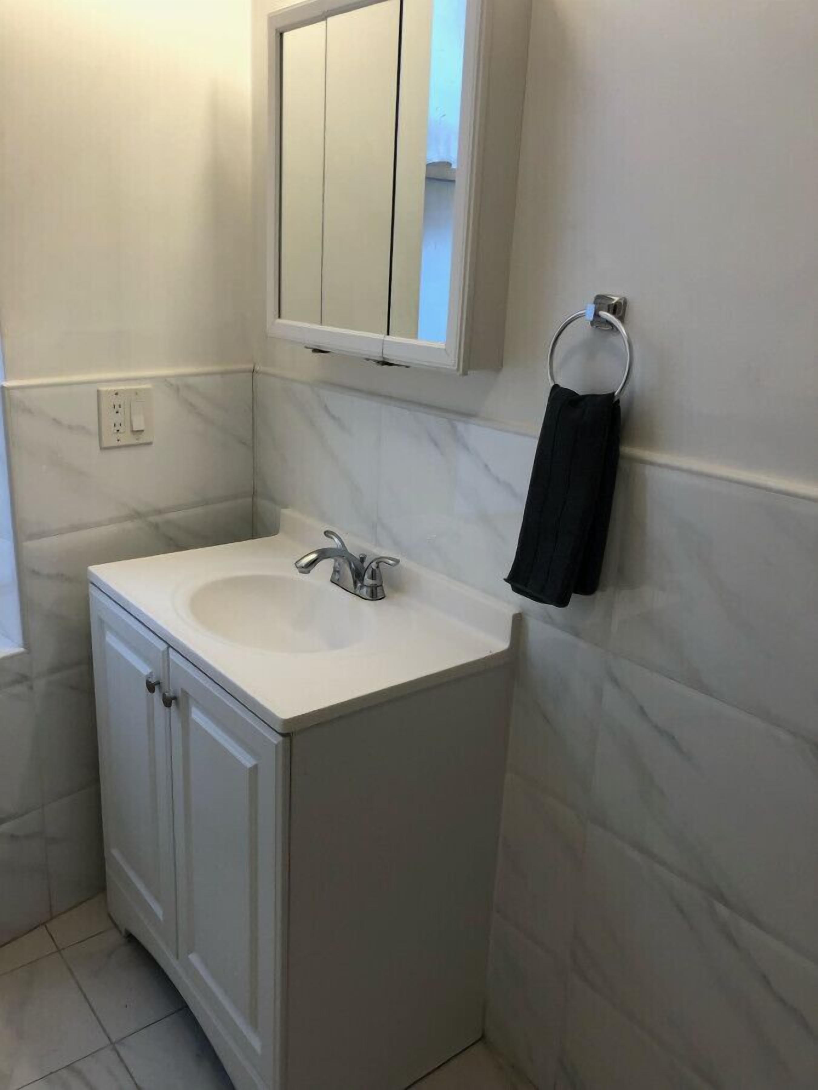 Ein Badezimmer mit einem weißen Waschbecken, einem Spiegel und einem Handtuchhalter an der Wand.