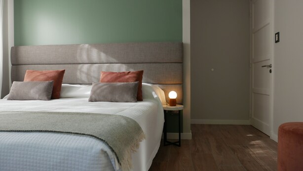 A neatly made bed with pillows, a bedside lamp, and a nightstand. - Double Queen Size with Private Bathroom (Mendoza)